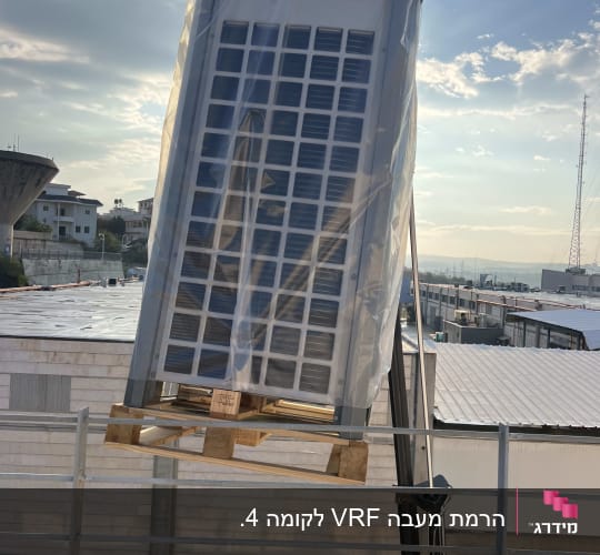 הרמת יחידת מיזוג תעשייתית לגובה באמצעות מנוף זרוע